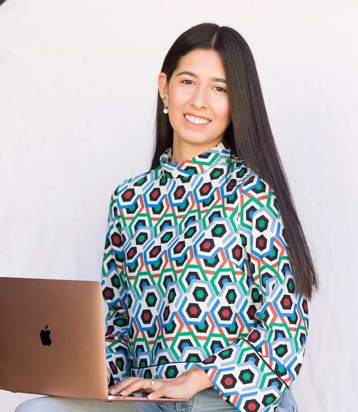 Carolina Marcos smiling, sitting with a laptop on her lap