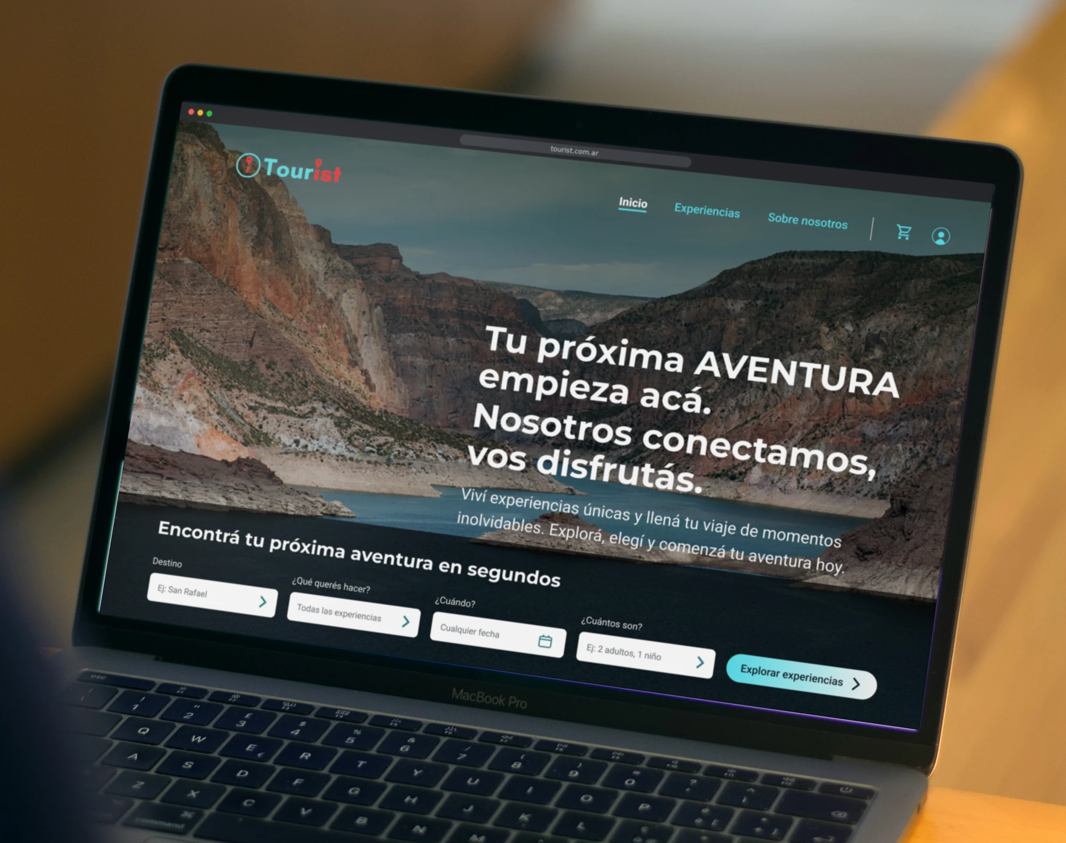 A person working on a laptop in an office, with the redesigned Tourist homepage on screen: a canyon photo, the headline 'Tu próxima AVENTURA empieza acá' and the search bar
